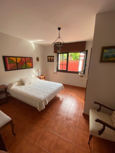 Habitación 3 Habitación luminosa con cama doble, sillas y ventanas con vistas al exterior.