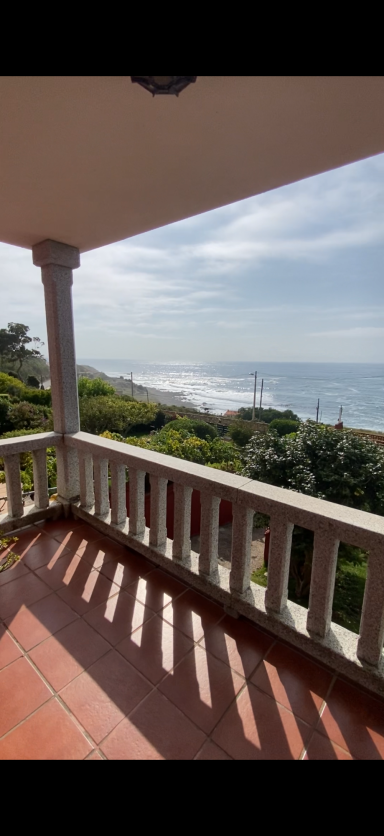Terraza planta alta Vista desde un balcón con mar y vegetación al fondo, luces y sombras marcadas.