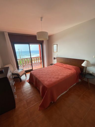 Habitación principal Habitación con cama doble, balcón con vista al mar y decoración en tonos cálidos.