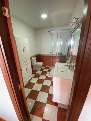 Baño habitación principal Baño moderno con inodoro, lavabo y ducha, con azulejos en blanco y rojo.